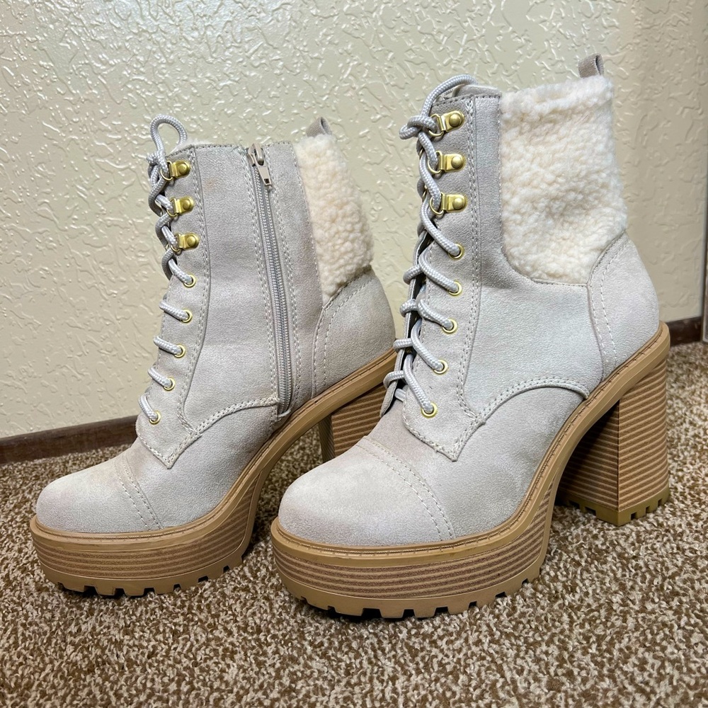 Heeled combat boots on gray with a detail on white closer to cream at the back.